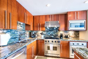 Una cocina moderna con armarios de madera, estufa de acero inoxidable y microondas.