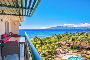 Ein Balkon mit Korbmöbeln und Blick auf das Meer und die Berge.