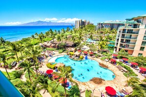 Un resort con una piscina grande, palmeras y vista al océano.