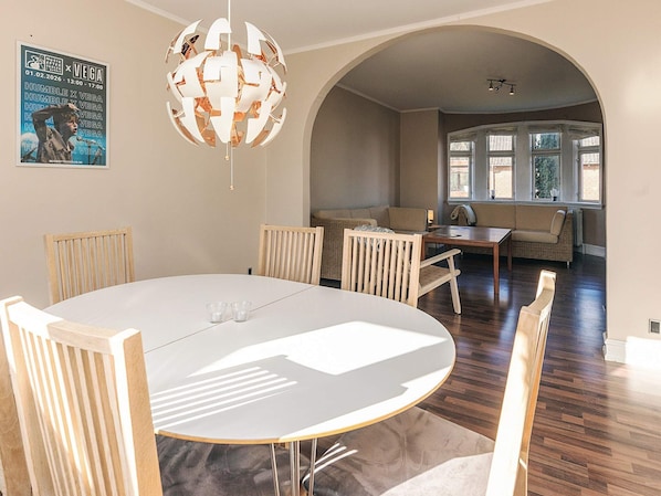 A dining area with a round table, chairs, and a hanging light fixture.