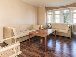 A living room with a sofa, a table, and a window with curtains.