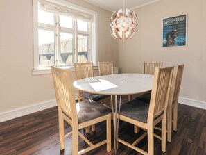 A dining area with a round table, six wooden chairs with cushioned seats, a hanging light fixture, and a poster on the wall. - 5 Person Holiday Home in Tranekaer (Tranekaer)