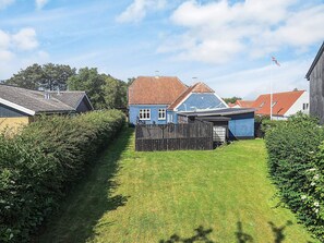 A residential area with a blue house, a wooden fence, and a clear sky. - 5 Person Holiday Home in Tranekaer (Tranekaer)