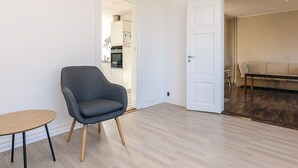 En moderne stue med en grå lænestol, et rundt sofabord og en sofa.
