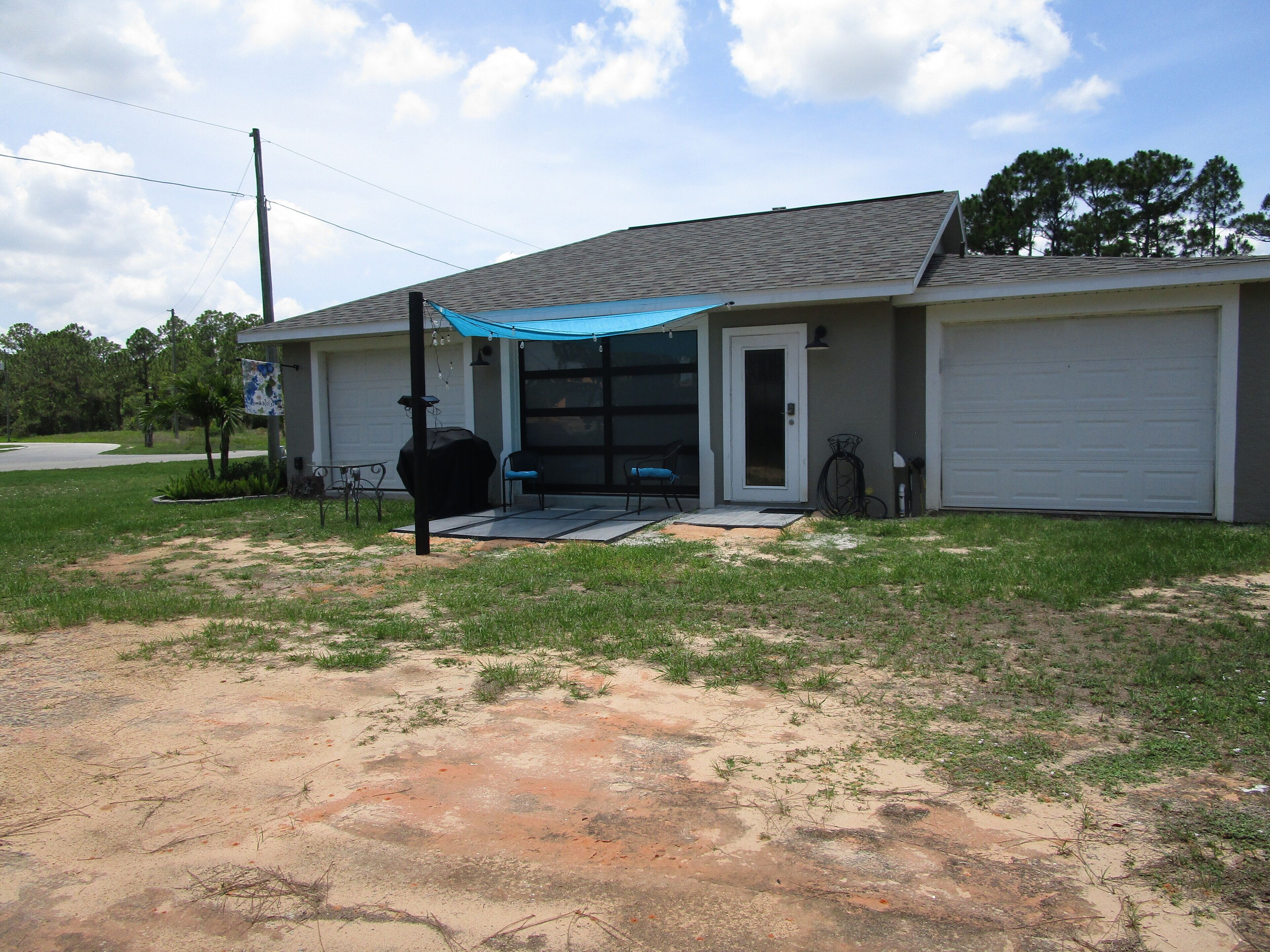 Une maison de plain-pied avec un patio couvert, un garage et une pelouse.