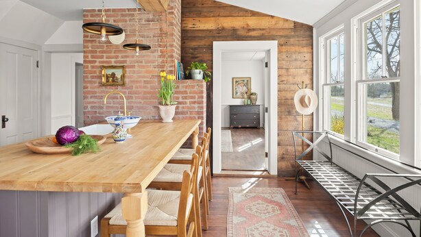 A kitchen with a wooden island, a brick wall, and a view of the outdoors. - Farmhouse Retreat, Infrared Sauna, Fire-Pit, Fast Wifi, Golf & 3-Acre Privacy (Valatie)
