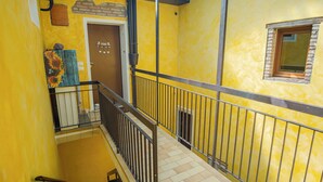 Un interior amarillo con una escalera, una puerta que dice 'HOME' y un ventanal con vistas.