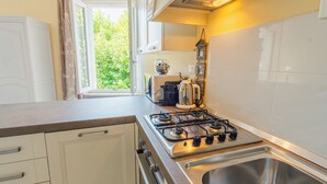 Una cocina con estufa a gas, un lavamanos y una ventana con vistas al follaje.