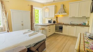Habitación de hotel pequeña con cama, una kitchenette y una ventana con cortinas.