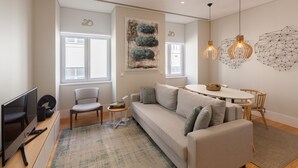 A modern living room with a sofa, a TV, and a dining table with chairs.
