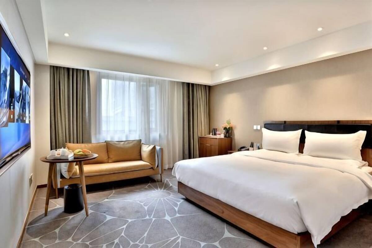 A hotel room with a bed, a sofa, a small table, and a nightstand.