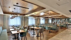 Een moderne eetruimte met meerdere tafels en stoelen, een bar en een zithoek met comfortabele banken.