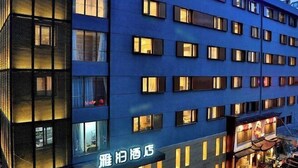Een hotel met meerdere verdiepingen, een blauwe gevel en verlichte ramen.