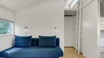 A room with a blue sofa, white walls, and a wooden floor.