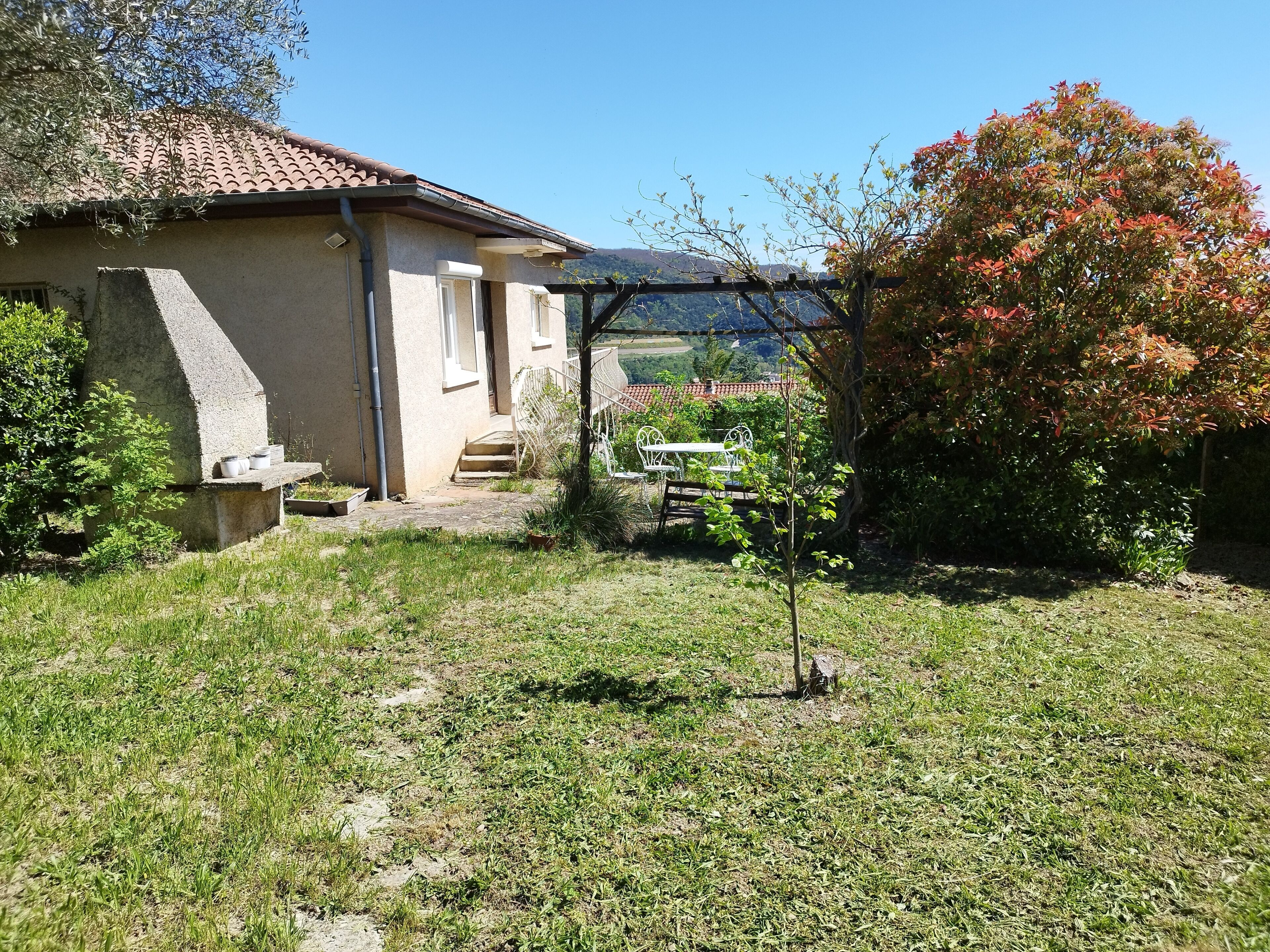 Une maison avec un patio, un petit jardin et une vue sur la campagne.