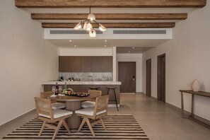 A modern kitchen with a central island, wooden ceiling beams, and a dining area with a round table and chairs.