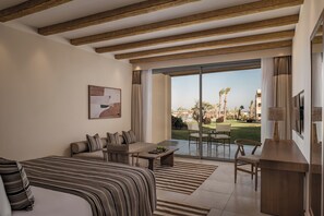 Ein Hotelzimmer mit Bett, Sofa, Esstisch und Blick auf Garten und Gebäude.