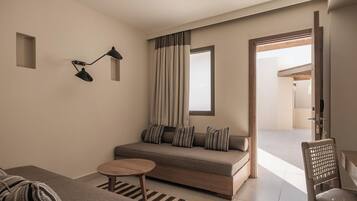 A modern living room with a sofa, a small round table, a lamp, and a view through an open door.