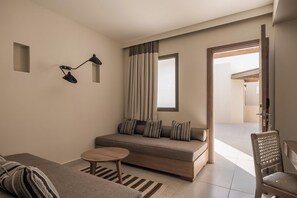 Ein modernes Wohnzimmer mit einer Couch, einem kleinen runden Tisch, einer Lampe und Blick durch eine offene Tür.