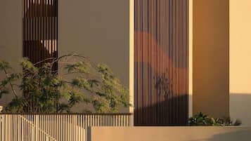 Um edifício moderno com ripas verticais, base de concreto e um espelho d'água na frente.