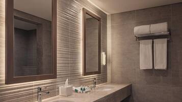 A modern bathroom with a large mirror, two sinks, and a towel rack.