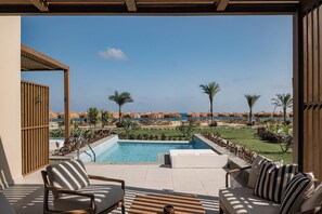 A poolside area with lounge chairs and a view of the beach. - JAZ Elite Riviera (Marsa Alam)