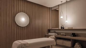 A modern spa room with a wooden wall, a round light fixture, a bench, and a vanity with towels.