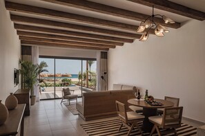 A modern interior with a dining area, sofa, and a view of the beach. - JAZ Elite Riviera (Marsa Alam)