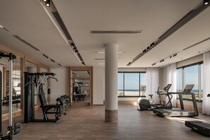 A modern gym with exercise equipment, large windows, and a view of the ocean. - JAZ Elite Riviera (Marsa Alam)