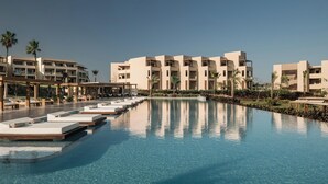A resort with a swimming pool, multiple-story buildings, and palm trees.