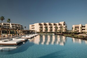 A resort with a swimming pool, multiple-story buildings, and palm trees.