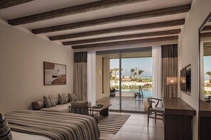 A modern hotel room with a large bed, a sofa, a desk, and a balcony with a pool view. - JAZ Elite Riviera (Marsa Alam)