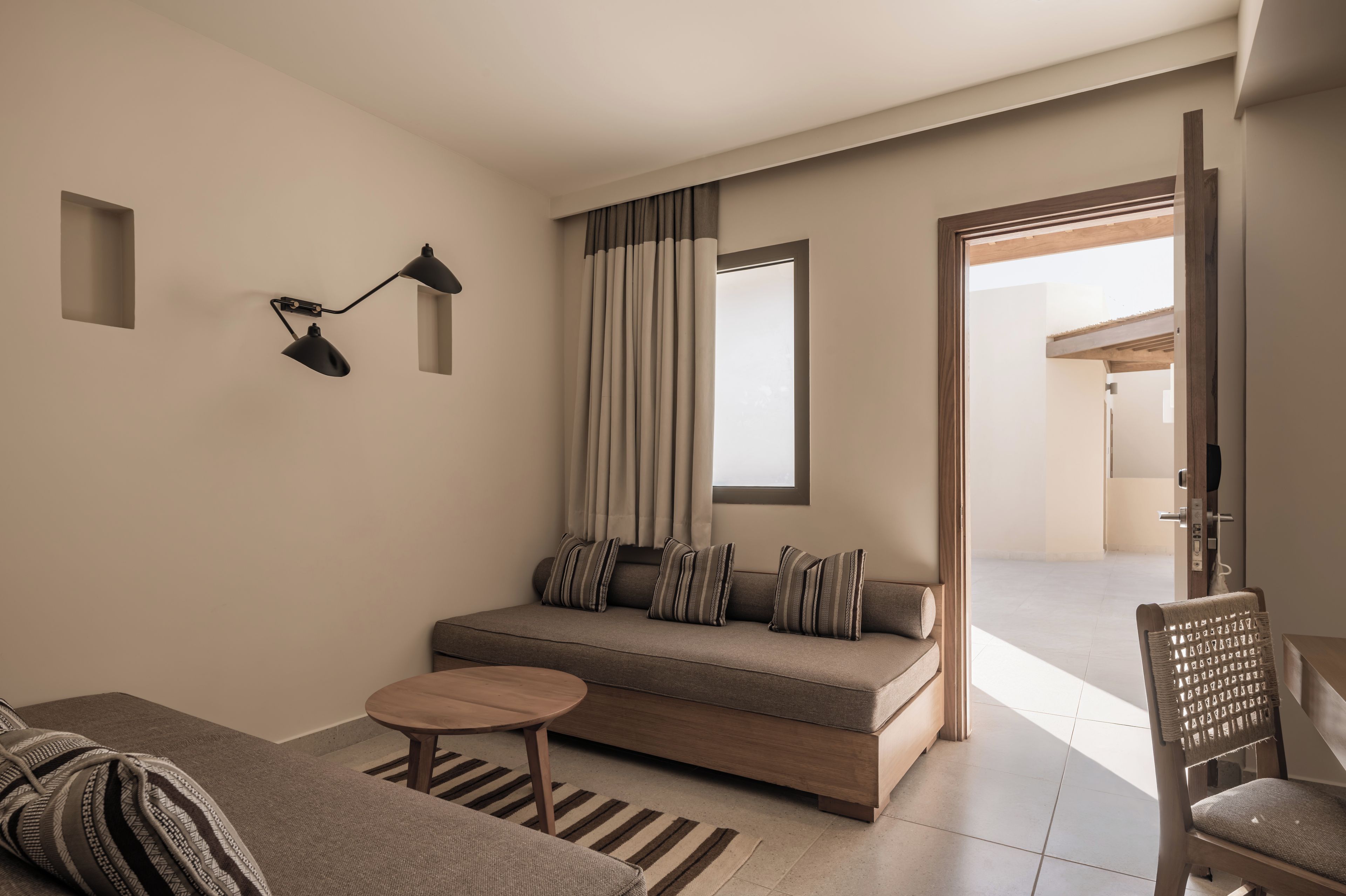 Ett modernt vardagsrum med en soffa, ett litet runt bord och en vägglampa.