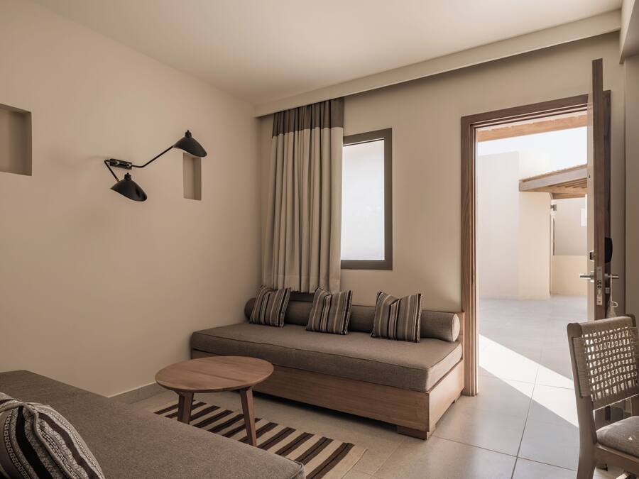 A modern living room with a sofa, a small round table, and a wall-mounted lamp.