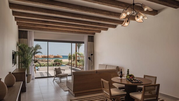 A modern room with a view of the beach, a dining area, and a sofa.