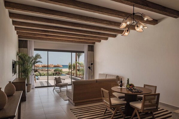 A modern room with a view of the beach, a dining area, and a sofa.