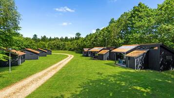 A campground with multiple cabins, a gravel path, and surrounding greenery.