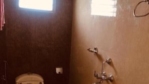 A small bathroom with a toilet, a sink, and a window. - MM Park Inn (Mahabalipuram)
