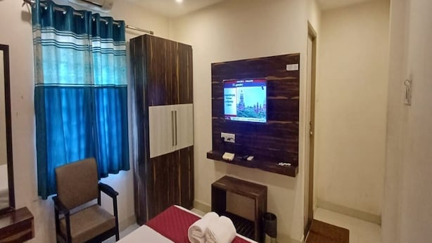 A hotel room with a bed, a chair, a TV, and a small table. - MM Park Inn (Mahabalipuram)
