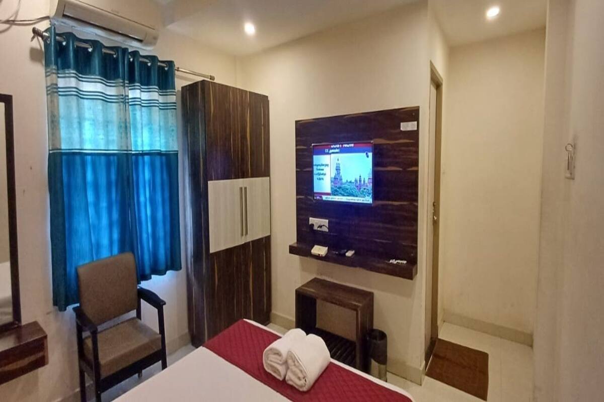 A hotel room with a bed, a chair, a TV, and a small table.