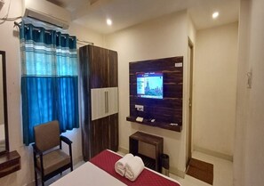 Een hotelkamer met een bed, een stoel, een televisie en een klein tafeltje.