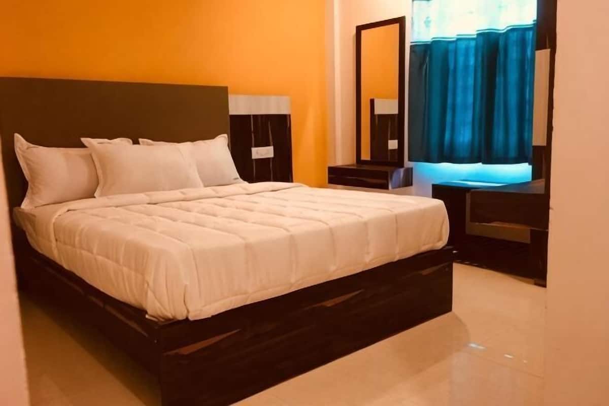 A bed with white bedding, a dark headboard, and a nightstand with a lamp.