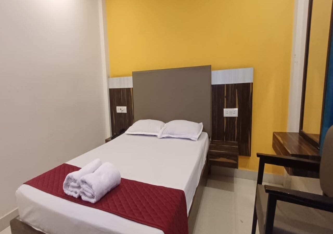 Una cama bien hecha con ropa de cama blanca y roja, un cabecero de madera y una mesita de noche de madera.