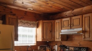 Una cocina estilo cabaña de madera con refrigerador, estufa, pileta y armarios de madera.