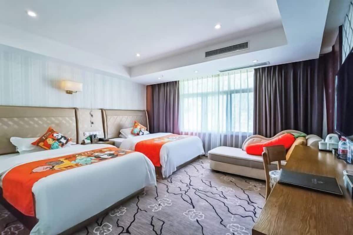 A hotel room with two beds, a sofa, a dining table, and a large window with curtains.