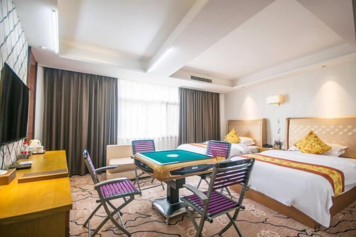 A hotel room with a bed, a desk, and a pool table.