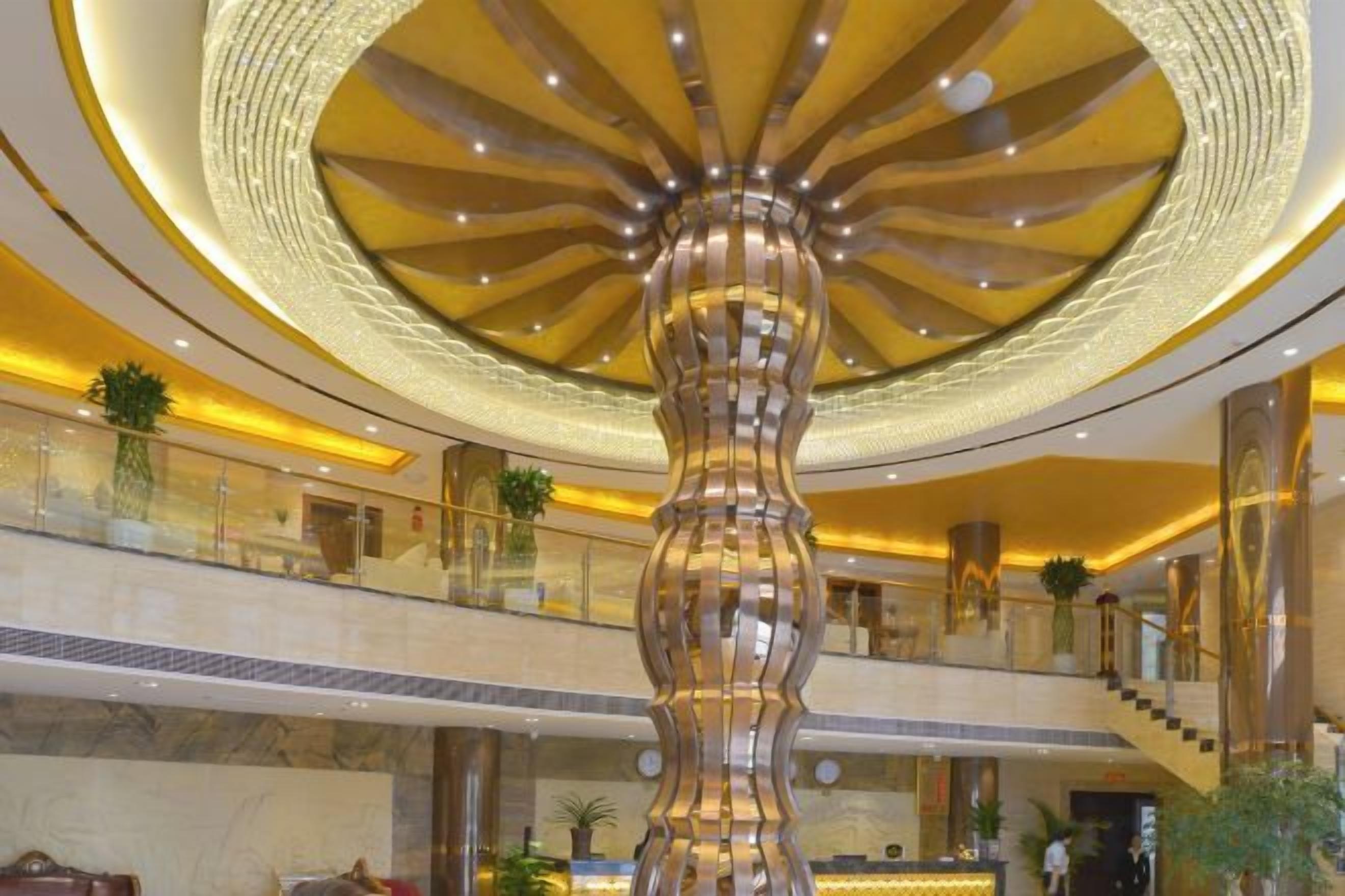 A lobby with a central column, a staircase, and a circular ceiling design.