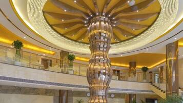 A lobby with a central column, a staircase, and a circular ceiling design.