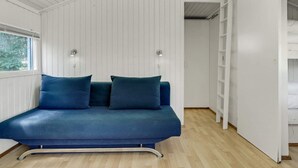 A room with a blue sofa, white walls, and a wooden floor. - 4 Person Holiday Home in Hampen (Hampen)