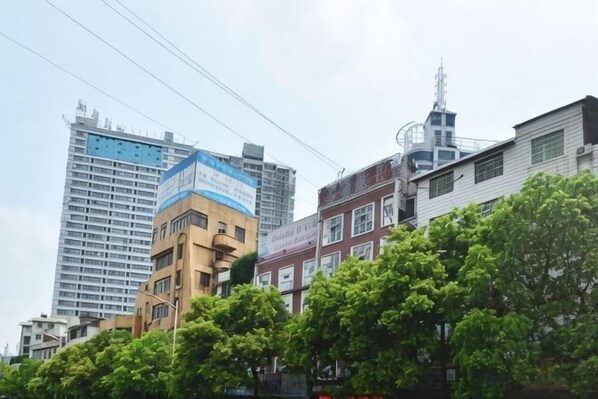 A multi-story building with a blue and white facade, surrounded by trees and other buildings. - HuaihuaHaiyi International Hotel (Huaihua Railway Station Xintiandi Plaza) (Huaihua)